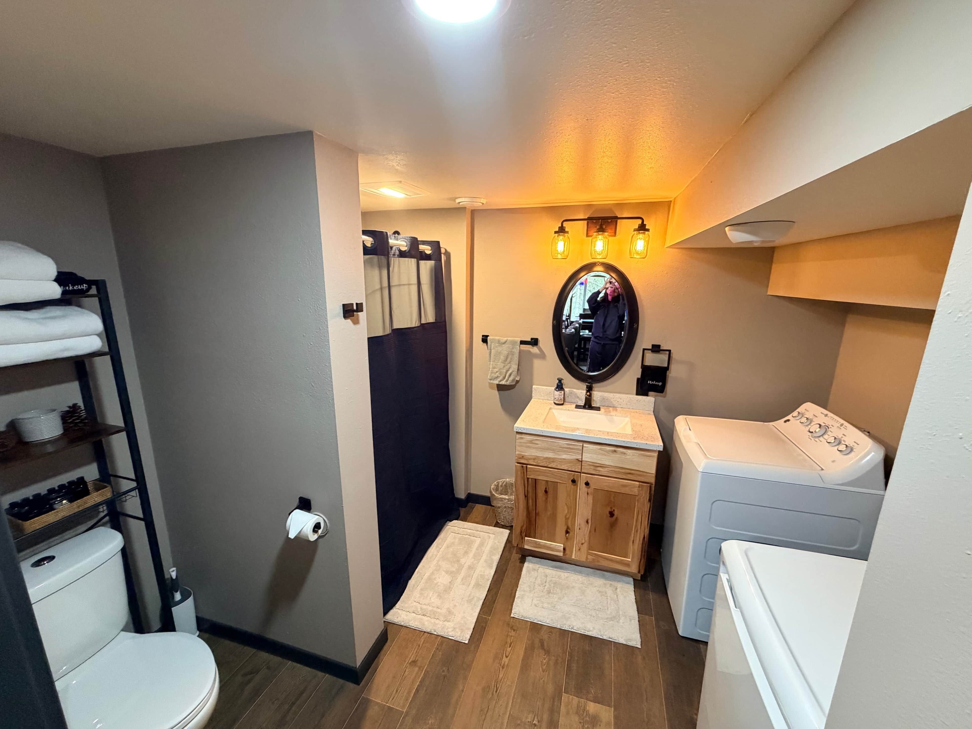 Un baño pequeño con inodoro, lavamanos, espejo y lavadora.
