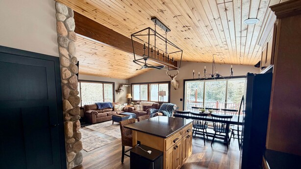 A spacious living area with a stone wall, wooden ceiling, and a large window.