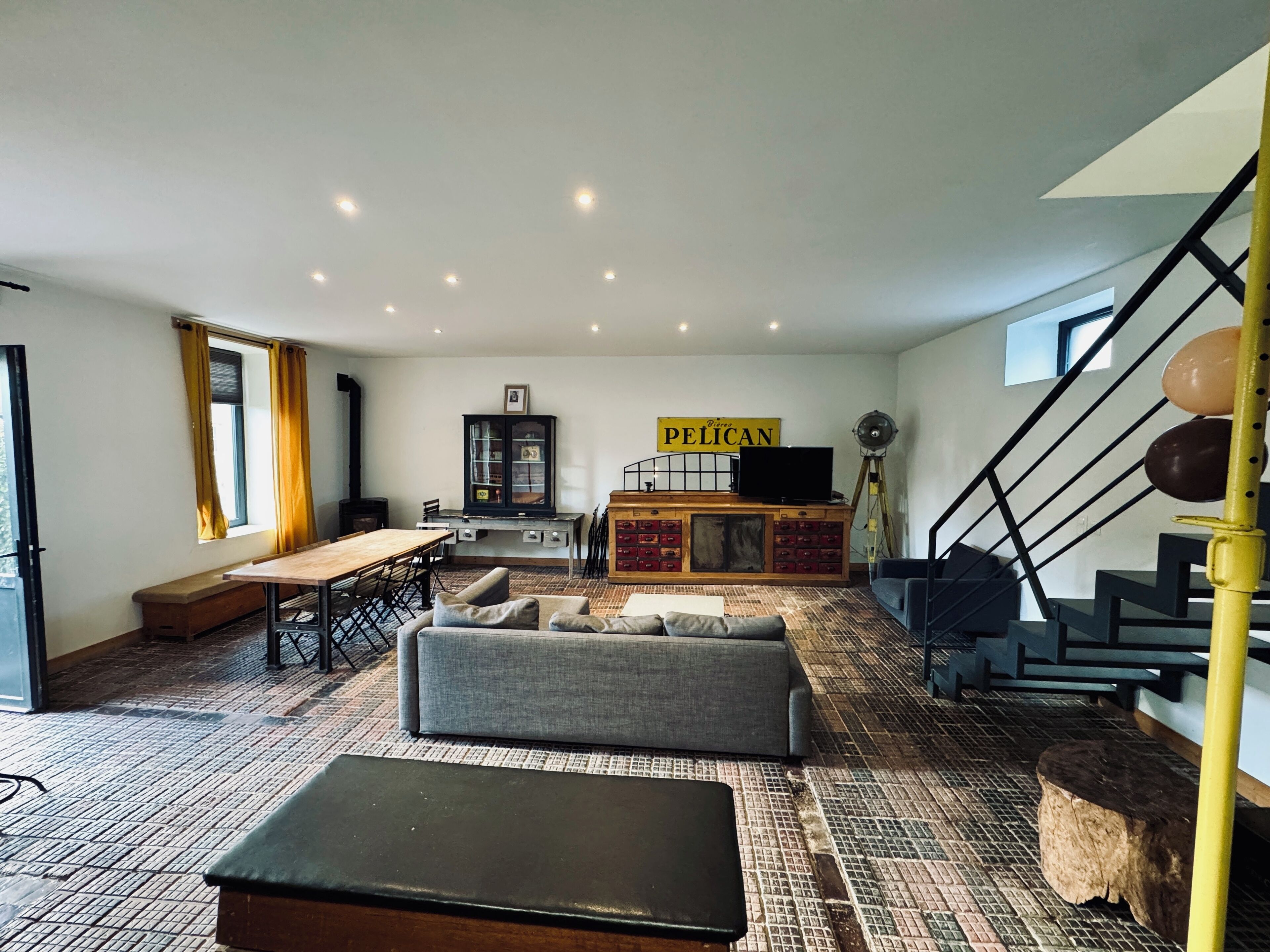 Ein geräumiges Wohnzimmer mit einer Couch, einem Holztisch, einem Schrank und einer Treppe.