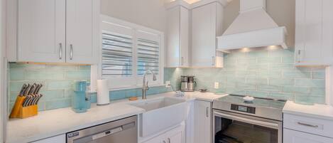 A modern kitchen with white cabinets, a stainless steel dishwasher, an oven, and a coffee maker.