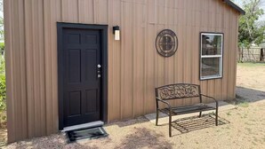 A metal shed with a black door, a welcome sign, and a bench outside. - Breakfast included/dartboard (Carlsbad)