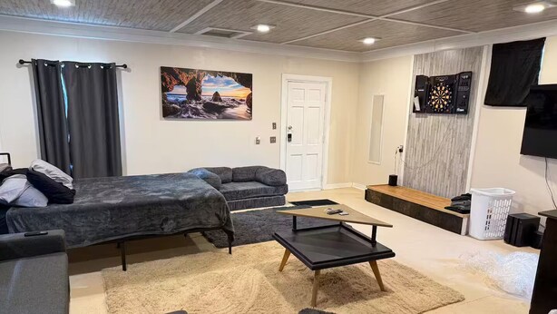 A modern living room with a sofa, a coffee table, and a TV. - Breakfast included/dartboard (Carlsbad)
