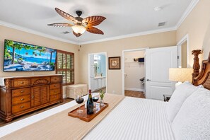 A bedroom with a bed, wooden dresser, television, and a ceiling fan. - Amazing Heated & Screen Pool w/ Stunning Design! (Crystal Beach)