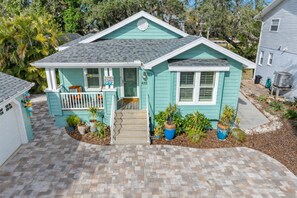 A two-story house with a front porch, a garage, and a driveway. - Amazing Heated & Screen Pool w/ Stunning Design! (Crystal Beach)