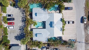 Vista aérea de un edificio con piscina, estacionamiento y vegetación circundante.