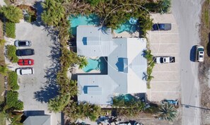 An aerial view of a building with a swimming pool, parking lot, and surrounding vegetation. - Coconut cottage Unit 1! (Holmes Beach)