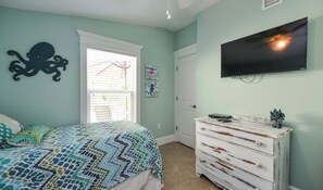 Ein Schlafzimmer mit Bett, Kommode, Fernseher und Kunstwerken.