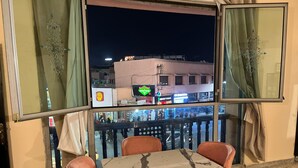Un balcon avec une table et des chaises, une vue sur une rue la nuit, et une enseigne Burger King.