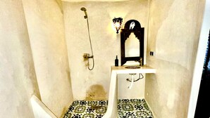 Une salle de bain avec une baignoire blanche, une douche et un lavabo agrémenté d’un miroir décoratif.