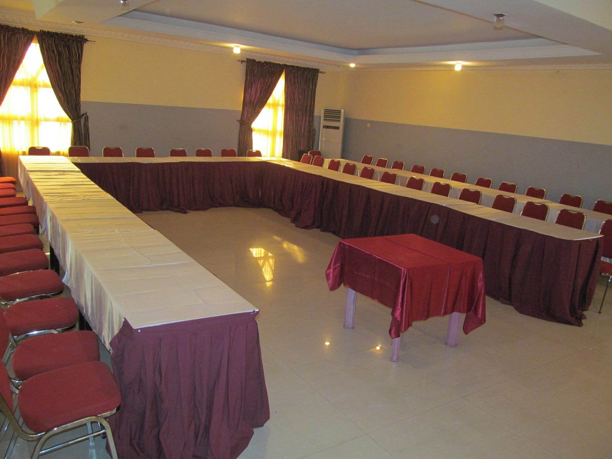 A conference room with a long table and chairs, a small table, and curtains.