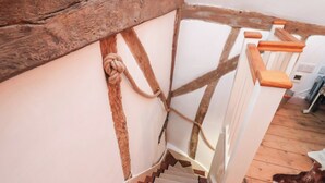 Eine Holztreppe mit Seil an der Wand, einem weißen Geländer und einem Holzboden.