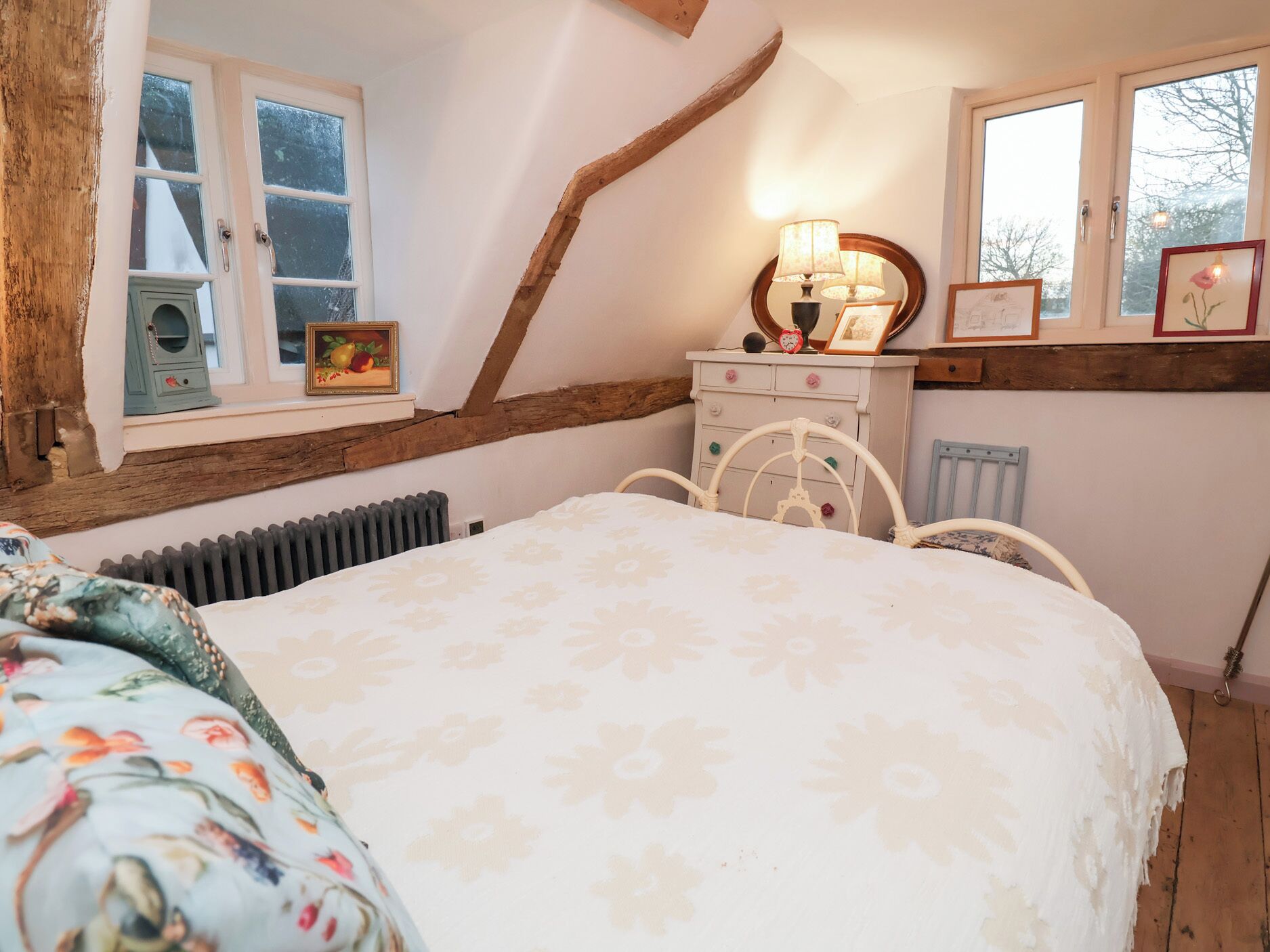 Een slaapkamer met een bed, een kaptafel en twee ramen.