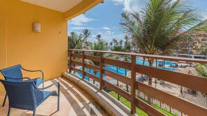 Ein Balkon mit Blick auf einen Pool und Palmen.