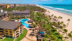 Ein Resort mit großem Pool, Strandlage und Palmen.