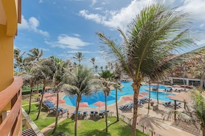 Un espace piscine agrémenté de palmiers, de chaises longues et de parasols.
