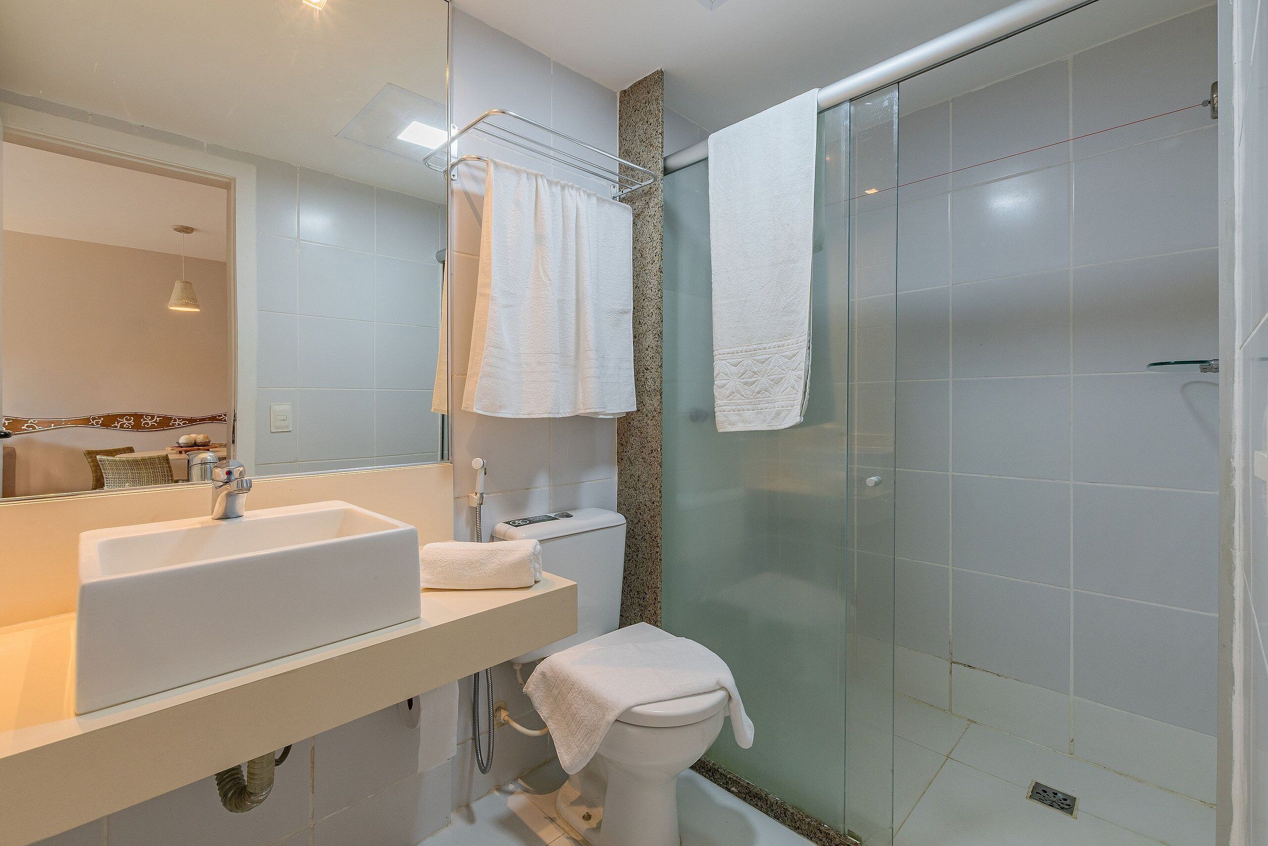 Une salle de bain équipée d’un lavabo, de toilettes et d’une douche à parois en verre.