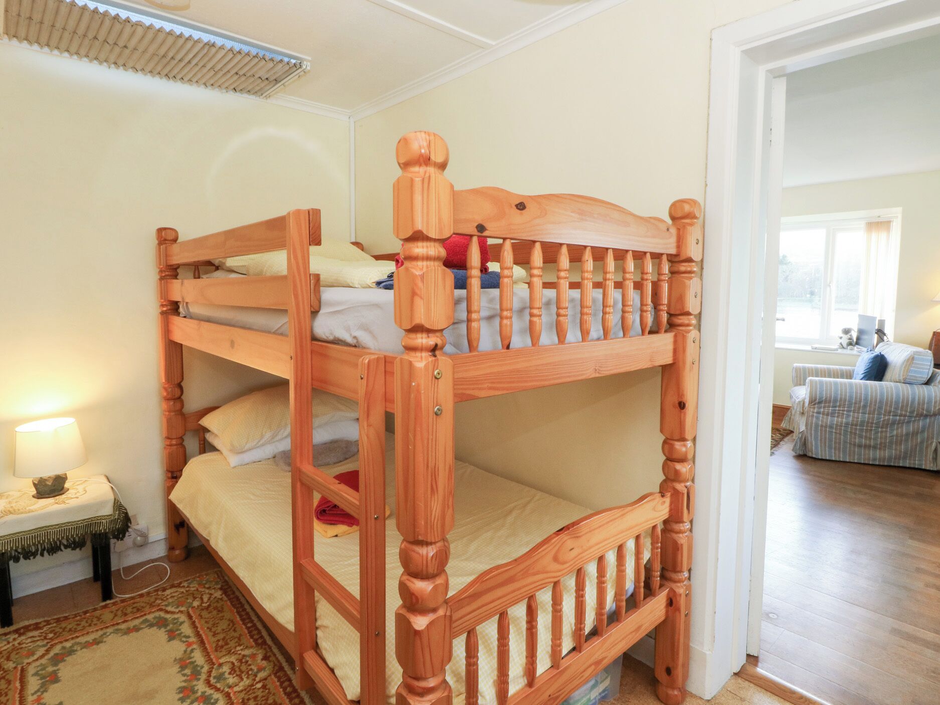 Un lit superposé avec une structure en bois et une petite table de chevet avec une lampe.