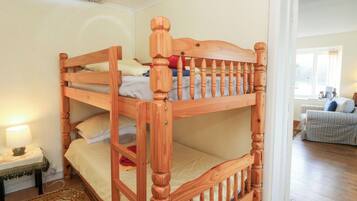 Un lit superposé avec une structure en bois et une petite table de chevet avec une lampe.