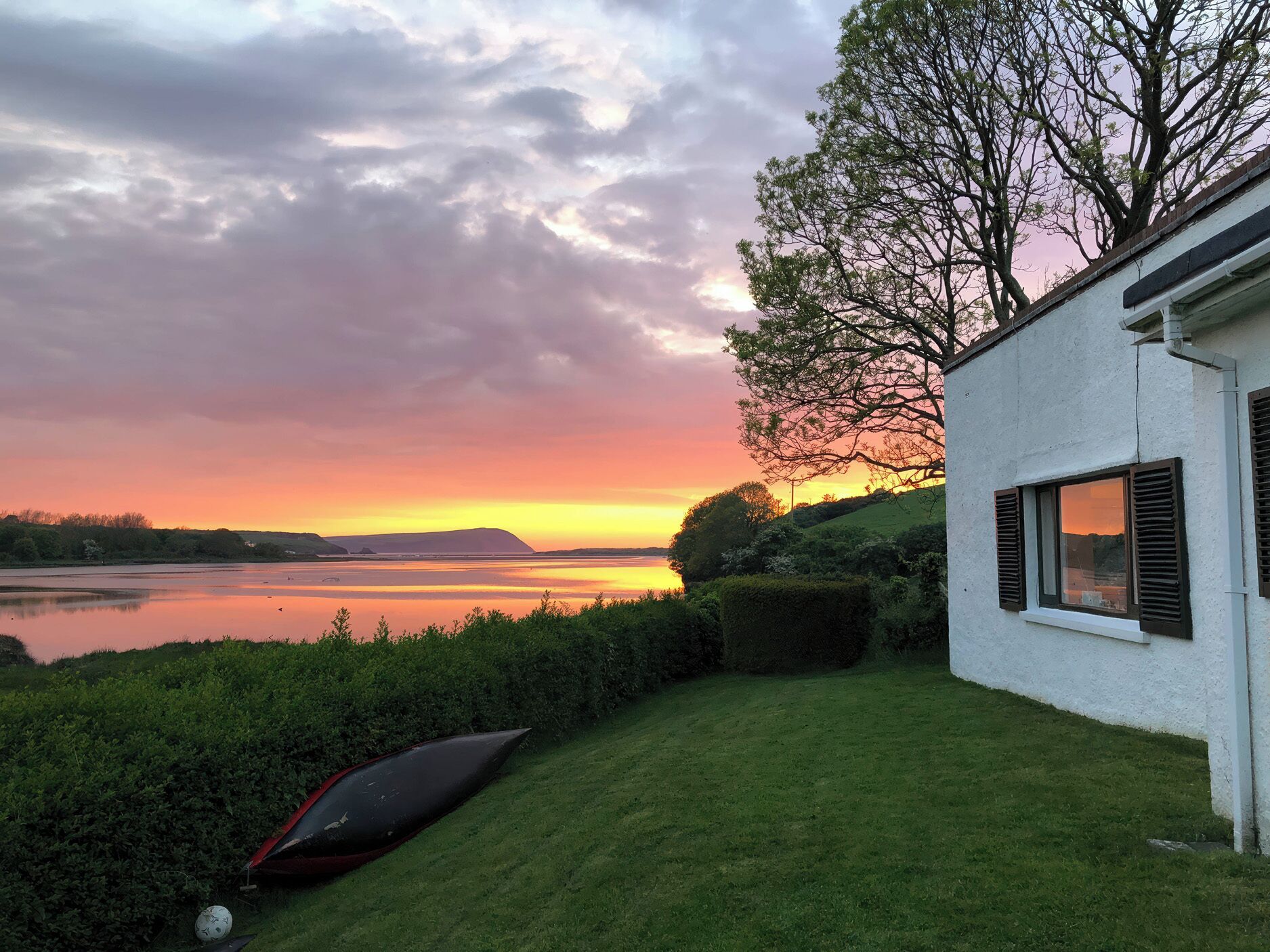 Una casa con vista a un lago y al atardecer.