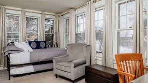 A bedroom with a bed, two armchairs, a wooden chair, and large windows. - Waterfront House w/ Patio Near Riverside Park (Kaukauna)