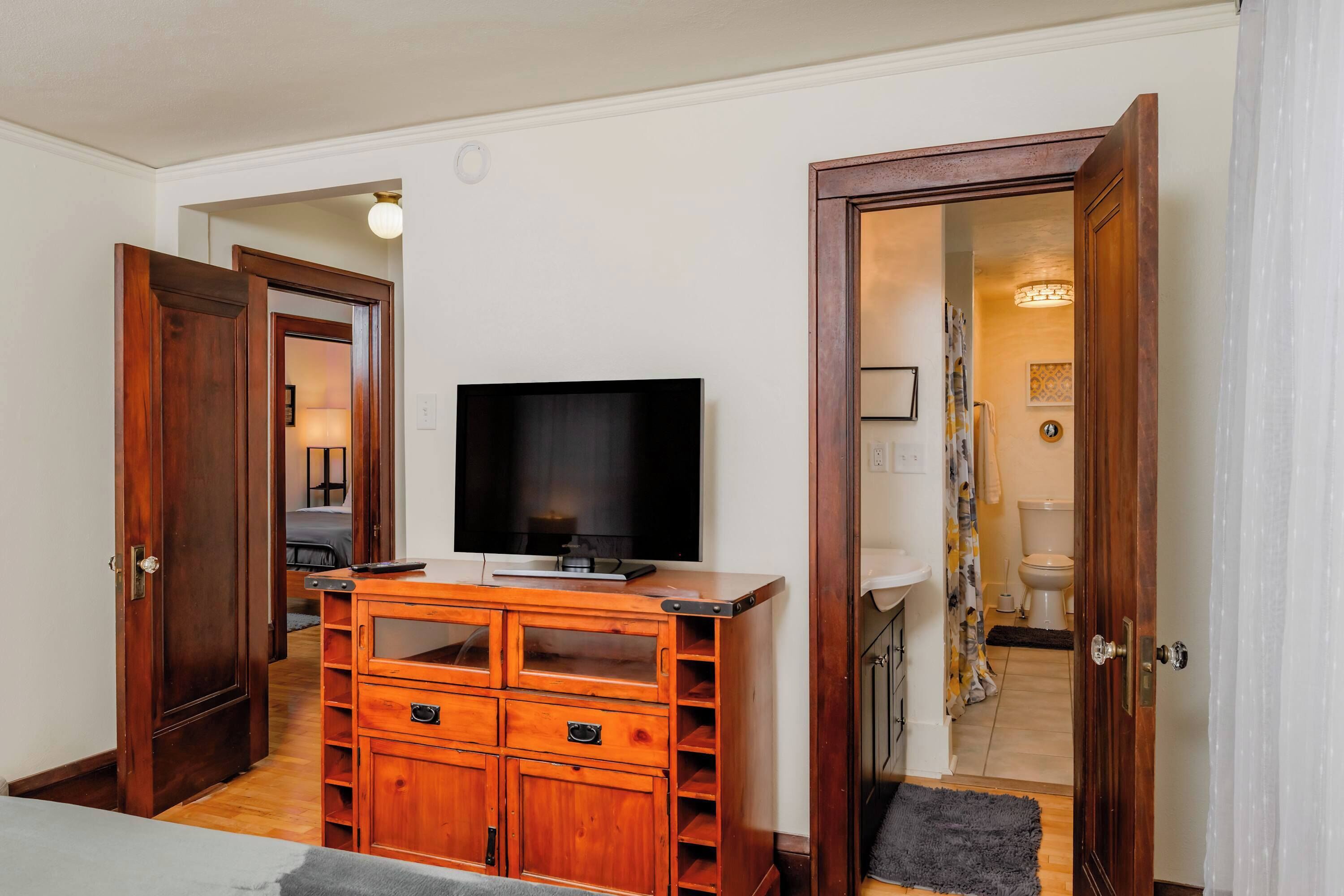 Ein Zimmer mit einem Holzkasten, einem Flachbildfernseher und einer Tür zu einem Badezimmer.