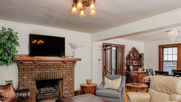 A cozy living room with a brick fireplace, leather furniture, and a television mounted above it. - Waterfront House w/ Patio Near Riverside Park (Kaukauna)