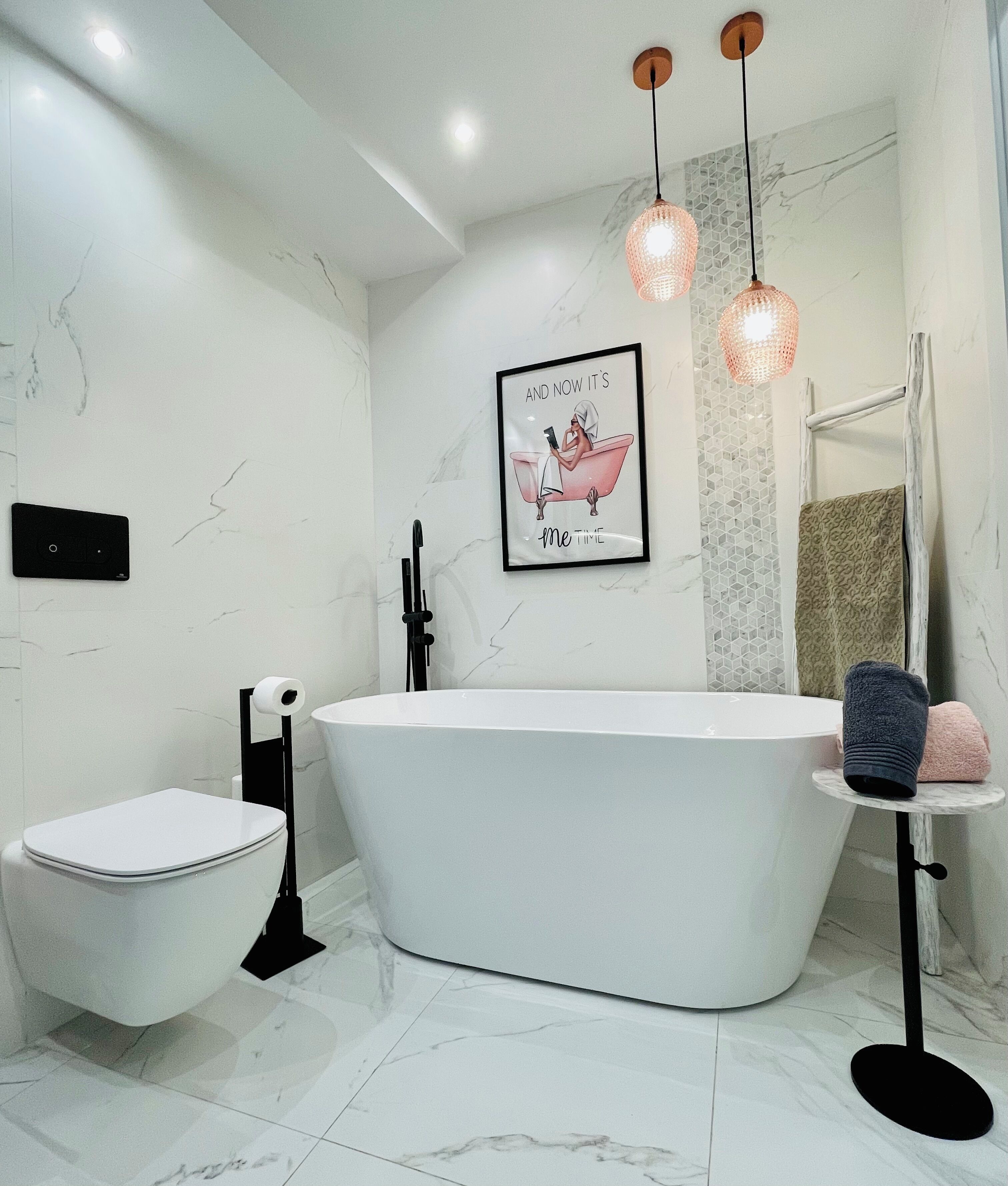 Un bagno moderno con una vasca da bagno indipendente, un water e un porta asciugamani.