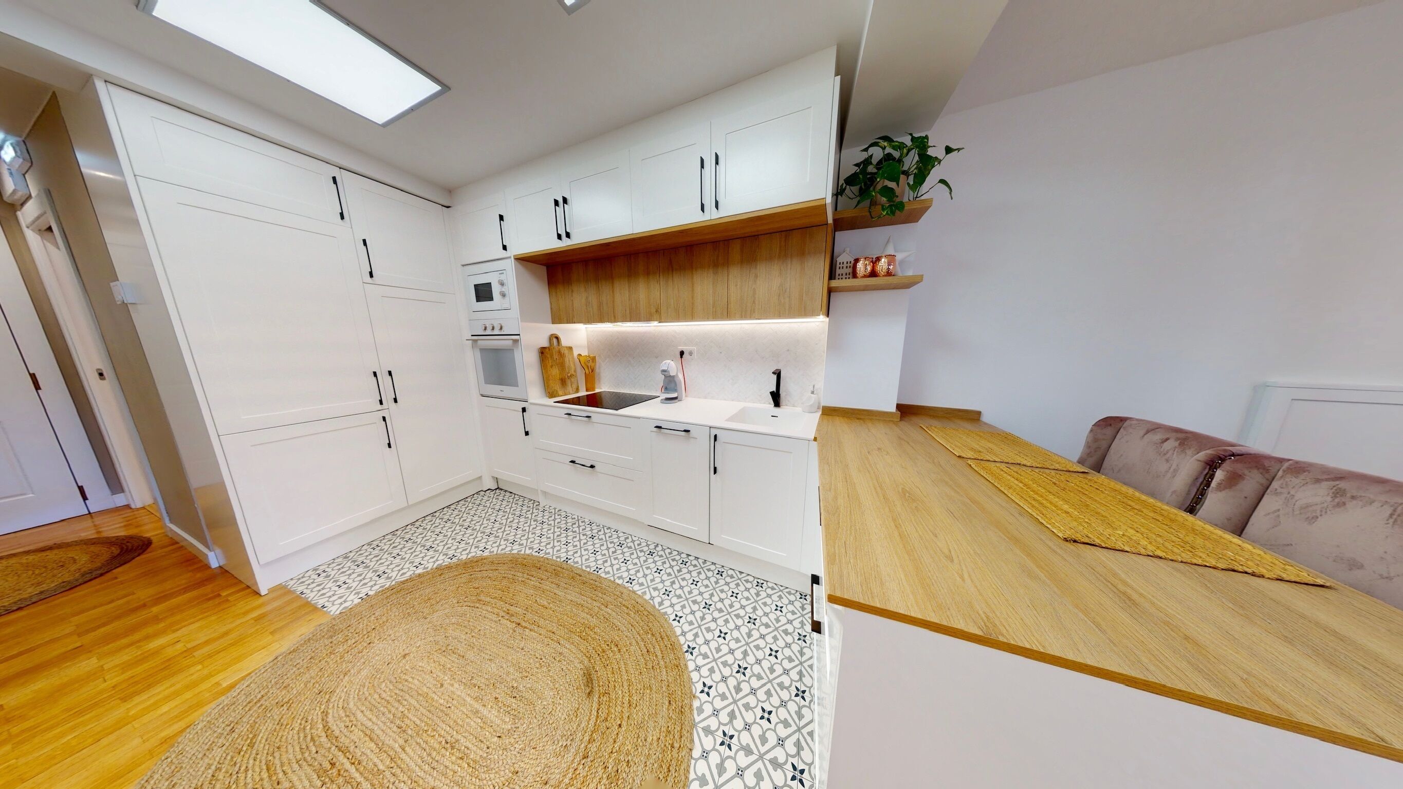 Een moderne keuken met witte kasten, een houten aanrechtblad en een vloer met een patroon.