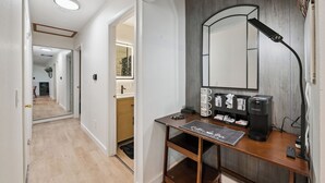 En hall med ett skrivbord i trä, en spegel, en kaffebryggare och en skylt på väggen.