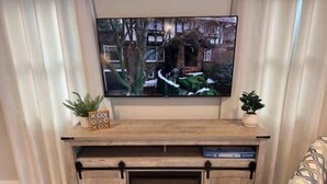 Una sala de estar con una televisión de pantalla plana instalada en un mueble de madera.