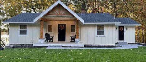A single-story house with a front porch, two windows on the side, and a door with a wreath.