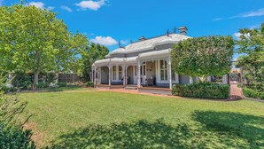 A white colonial-style house with a covered porch and a well-maintained lawn. - Central Charm - the best of Echuca living! (Echuca)