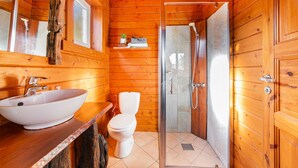 A wooden cabin bathroom with a large white sink, a toilet, and a glass-enclosed shower. - Le Studio Bleu - Jacuzzi Privé (Correns)