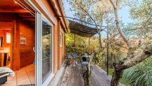 A wooden deck with outdoor seating, a pergola, and a view of the surrounding trees. - Le Studio Bleu - Jacuzzi Privé (Correns)