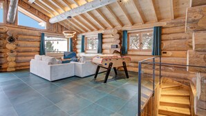 L’intérieur d’une cabane en rondins, avec un canapé, une table de baby-foot et un escalier.