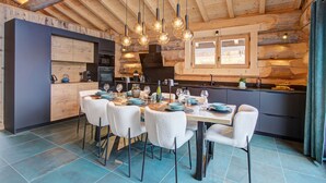 Une cuisine moderne avec un coin repas, dotée d’un plafond en bois, de luminaires suspendus et d’une grande fenêtre.