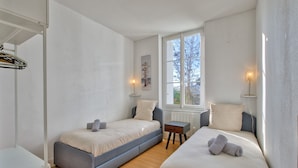 A bedroom with two beds, a small table, and a window. - La Villa Louise - Centre de Royan, proche plages (Royan)