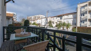 A balcony with wicker furniture, a table with a tray, and a view of residential buildings. - La Villa Louise - Centre de Royan, proche plages (Royan)