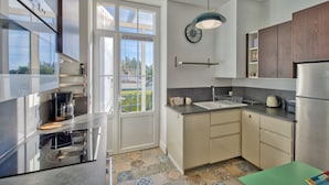 A modern kitchen with stainless steel appliances, a large window, and a view of greenery outside. - La Villa Louise - Centre de Royan, proche plages (Royan)