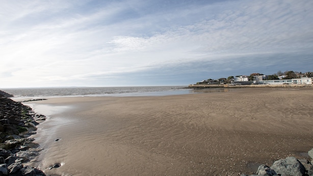 A wide sandy beach with a rocky shoreline and a row of buildings in the background. - La Villa Louise - Centre de Royan, proche plages (Royan)