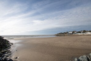 A wide sandy beach with a rocky shoreline and a row of buildings in the background. - La Villa Louise - Centre de Royan, proche plages (Royan)