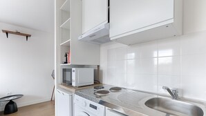 Eine moderne Küche mit eingebauter Waschmaschine und Trockner, einer Mikrowelle und einem Spülbecken aus Edelstahl.