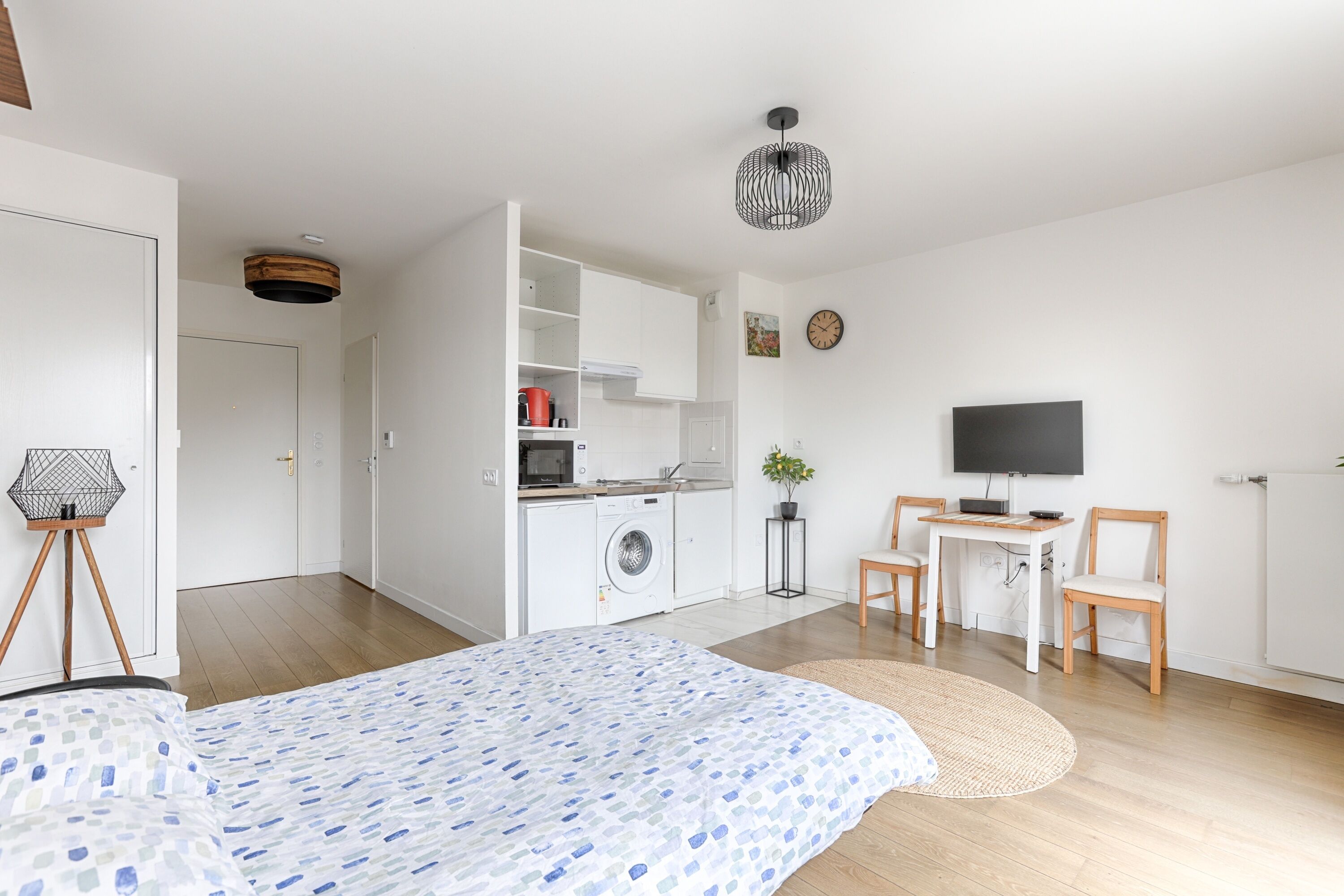 Una camera moderna e luminosa con un letto, angolo cottura, televisione e zona pranzo.