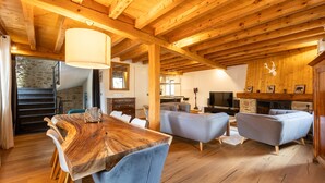 A spacious living area with a wooden ceiling, a dining table with chairs, and a sofa. - L’Écrin des Angles - Jacuzzi, Sauna, Hamman privé (Les Angles)