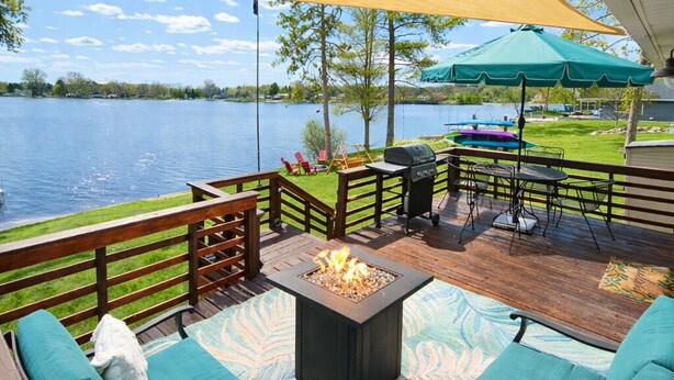 Une terrasse avec des sièges extérieurs, un foyer et une vue sur un lac.