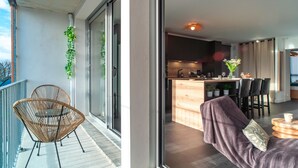 Un appartamento moderno con un balcone, una cucina con bancone e un'area pranzo.