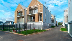 Un edificio residenziale moderno dal design simmetrico, caratterizzato da un balcone centrale e ampie finestre.