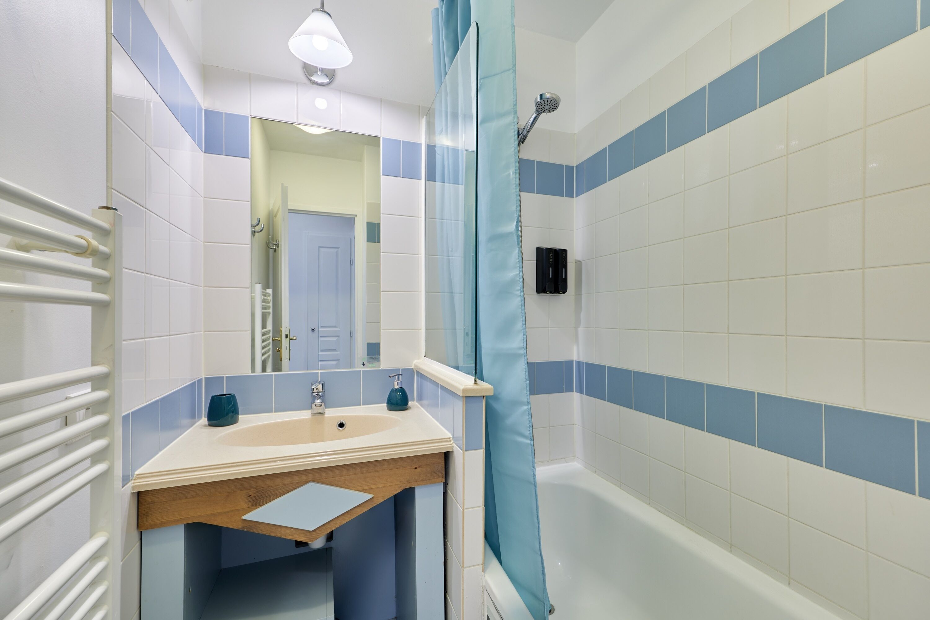 Ein Badezimmer mit Badewanne, Waschbecken, Spiegel und Duschvorhang.