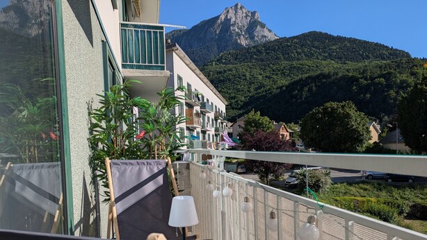 Een balkon met uitzicht op een berg, een tafel met een lamp en een stoel.