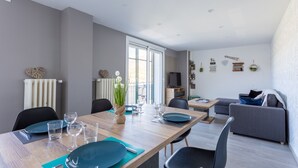 Een moderne woonkamer met een eethoek. Er is een bank, een televisie en een eettafel met stoelen.
